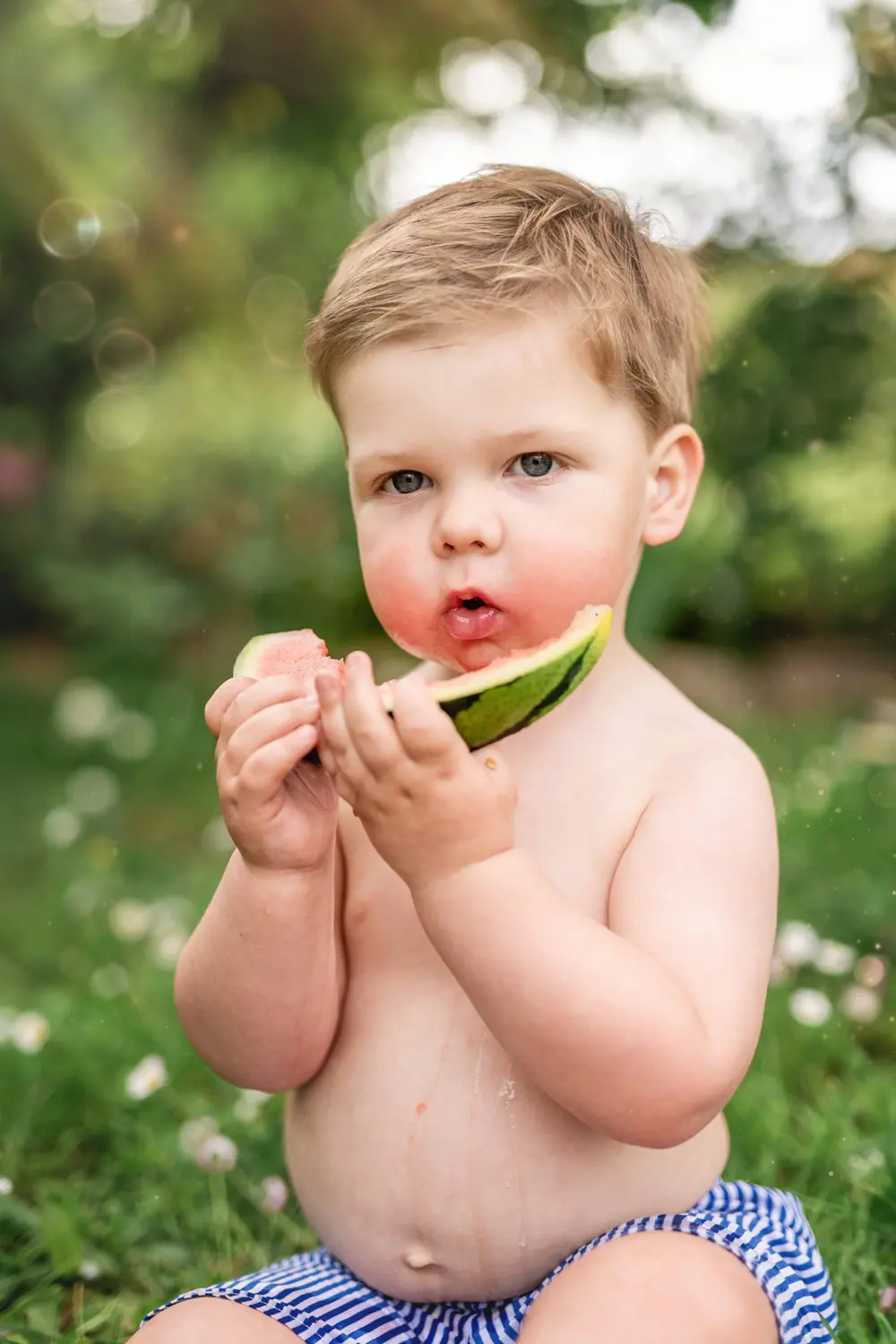 Enfant qui mange assis dans l'herbe. Photographe Famille à Nantes