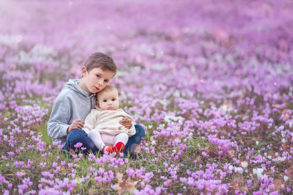 Frère et soeur se faisant un câlin dans les fleurs.