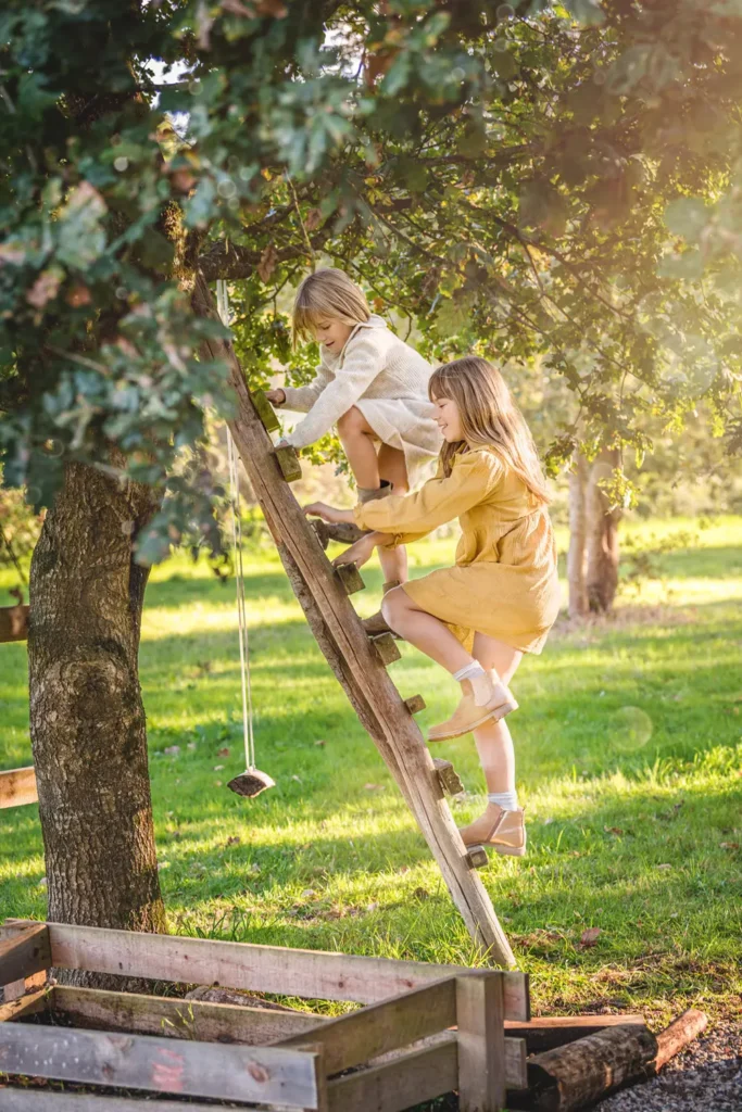 Soeurs qui montent à l'échelle sur un arbre avec la lumière du soleil.