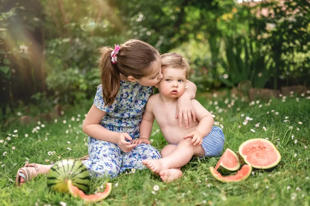 Frères et soeurs s'enlaçant assis dans l'herbe.