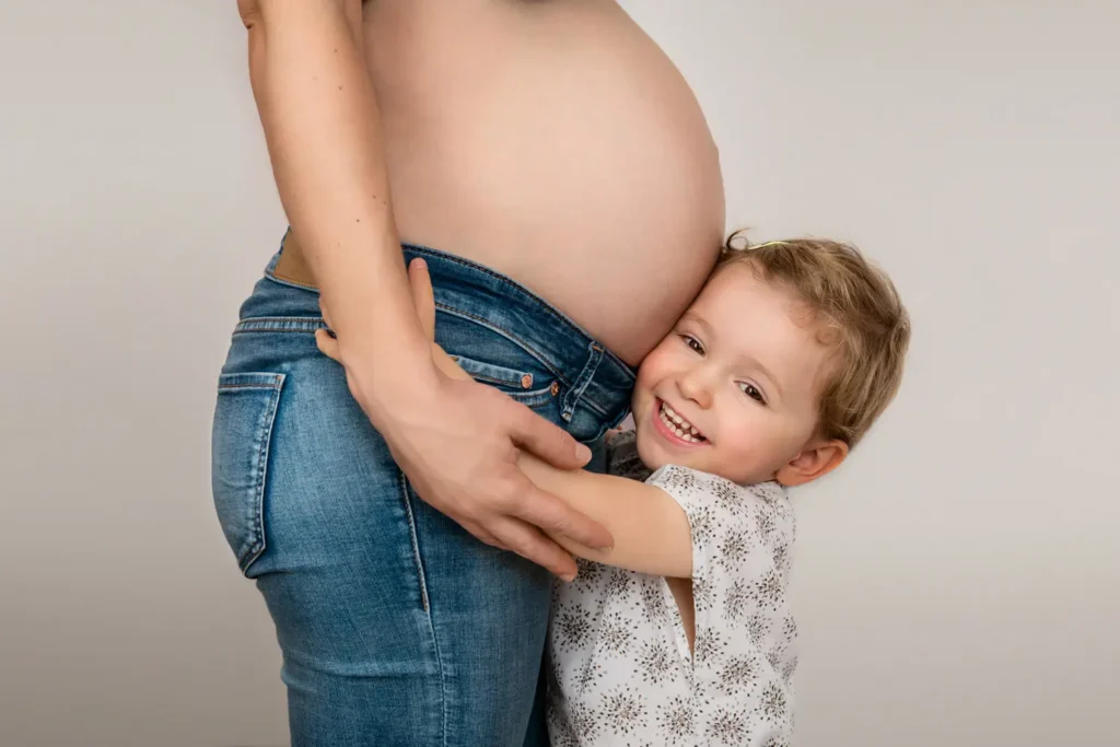Plan sur la grande soeur qui fait un câlin au ventre de sa mère