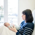 Maman qui tient son bébé sur ses genoux face à elle