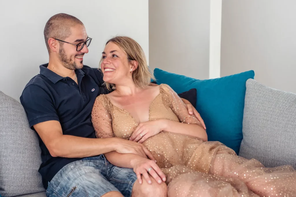 Femme enceinte et le papa qui s'enlace dans leur canapé