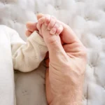 Plan sur les mains du nouveau né et de son père
