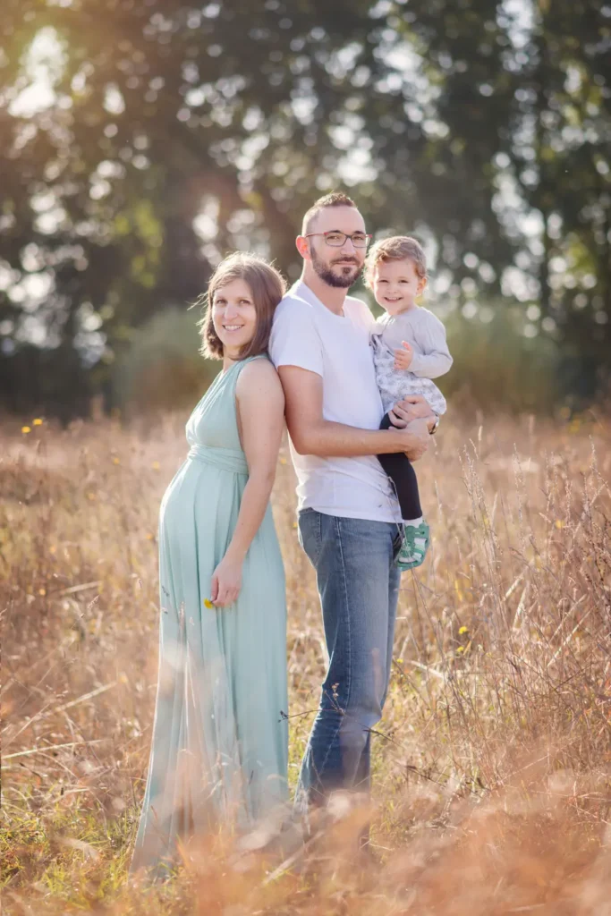 Famille debout sous des arbres, lumière douce.