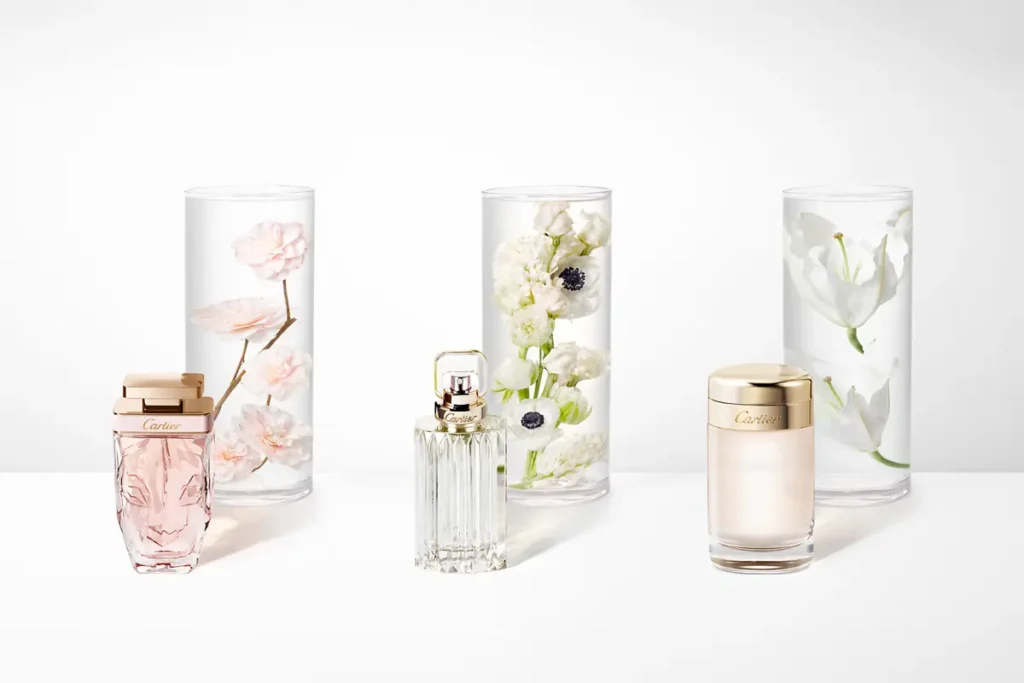 Flacons de parfum sur fond blanc avec, en arrière-plan, les plantes naturelles qui les composent.