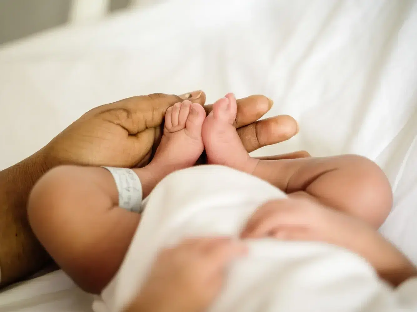 Plan sur les jambes de bébé qui sont tenus par la main d'un de ses parents