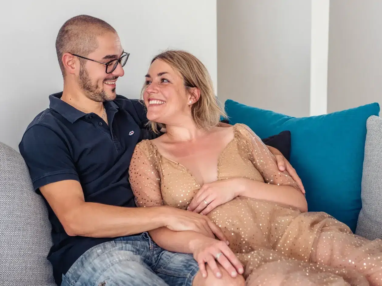 Femme enceinte et le papa qui s'enlace dans leur canapé
