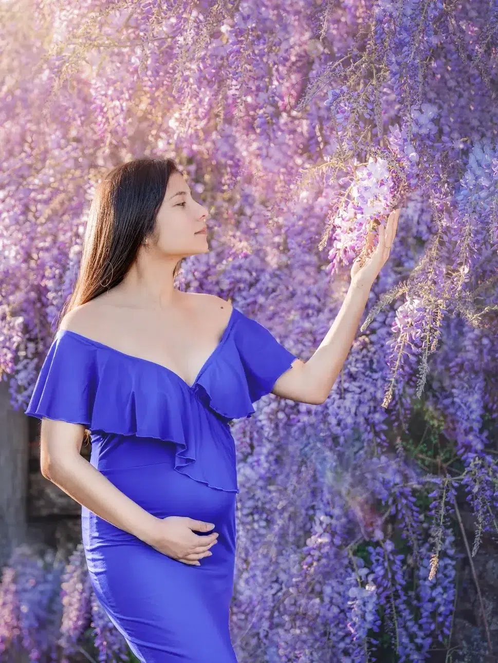 Femme enceinte qui tient son ventre et caresse un arbre fleurit